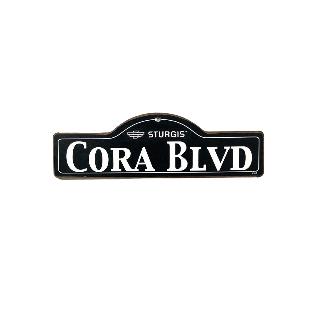 Cora Sturgis wooden street name sign with white lettering on black