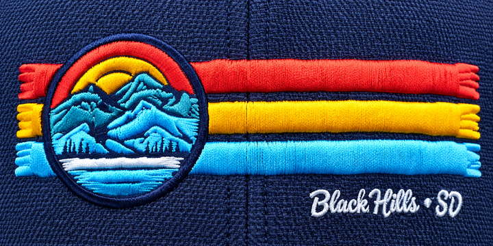 Close-up of raised red yellow and blue embroidery and mountain scene on Black Hills hat