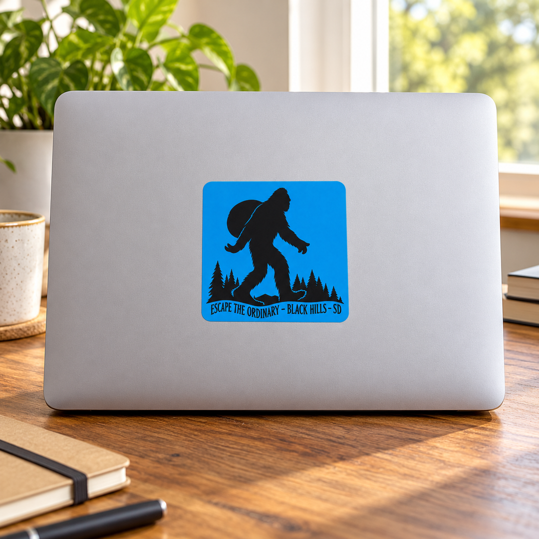 Black Hills Escape the Ordinary Bigfoot Backpacker Sticker on a laptop — lifestyle display mockup; accessories not included