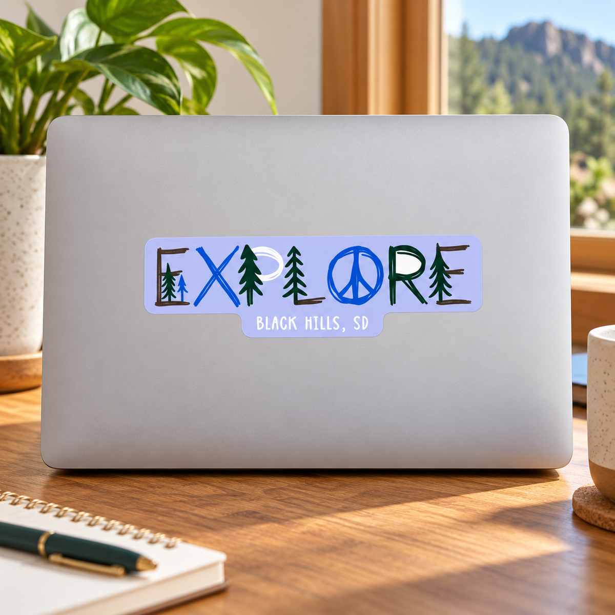 Black Hills Explore Pine Trees & Peace Sign Sticker on a laptop — lifestyle display mockup; accessories not included