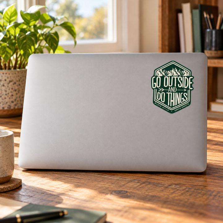Black Hills Go Outside and Do Things Hexagon Sticker on a laptop cover — realistic scale lifestyle display; accessories not included