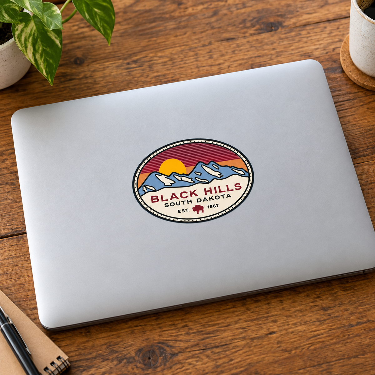 Black Hills Mountain Sunset Oval Sticker on a laptop — lifestyle display mockup; accessories not included