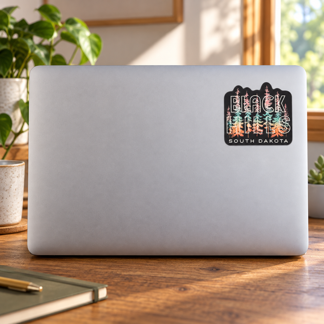 Black Hills Pastel Pine Tree Lettering Sticker on a laptop cover — realistic scale lifestyle display; accessories not included