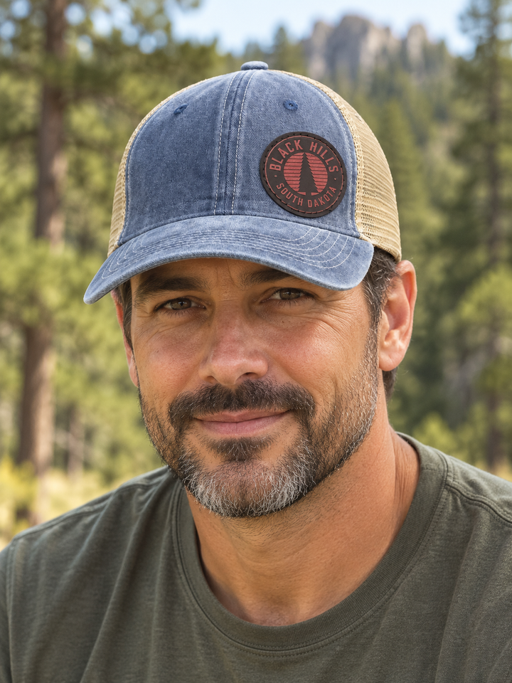 Black Hills Pine Tree Leather Patch Trucker Hat – Washed Blue &amp; Tan; male model wearing hat (AI-generated lifestyle image)