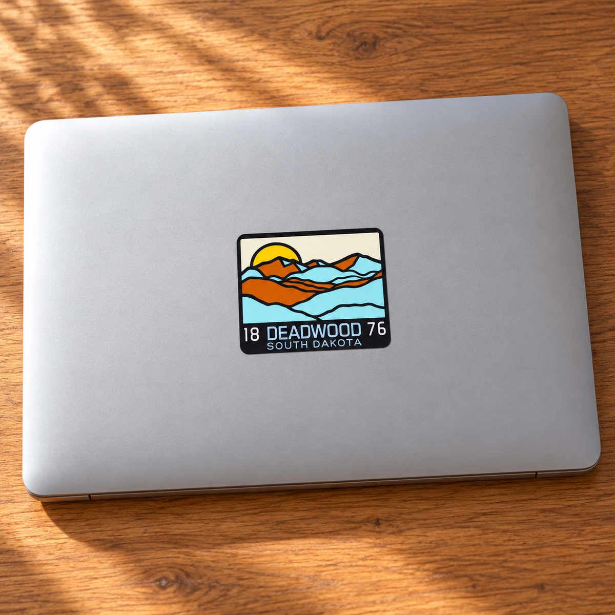 Deadwood 1876 Layered Mountains Sticker on a laptop — lifestyle display mockup; accessories not included
