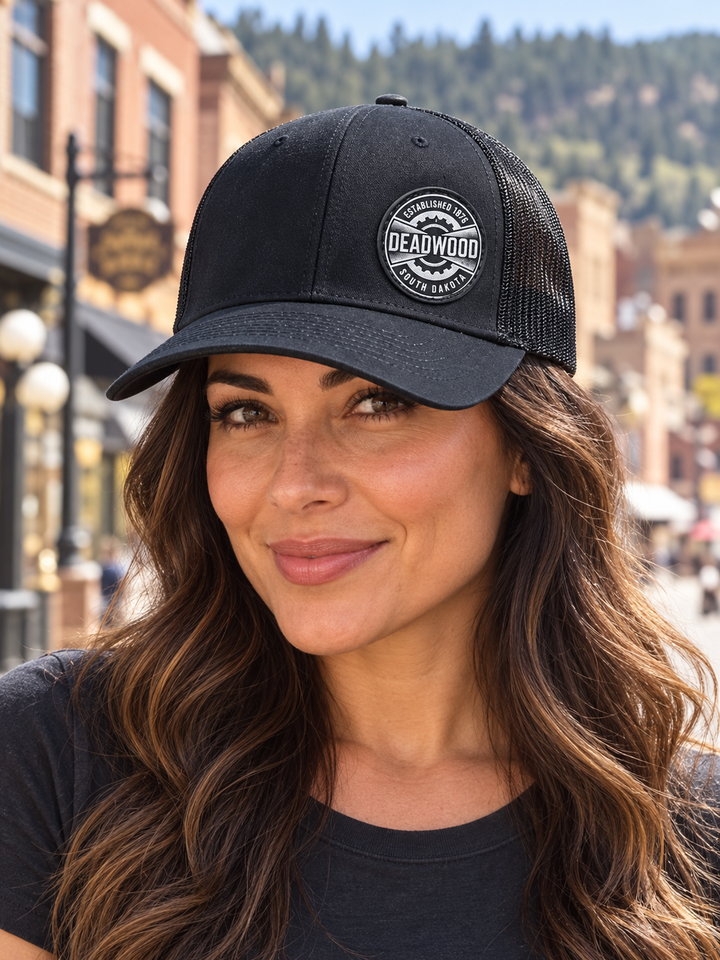 Deadwood Heritage Badge Leather Patch Trucker Hat – Black; female model wearing hat (AI-generated lifestyle image)