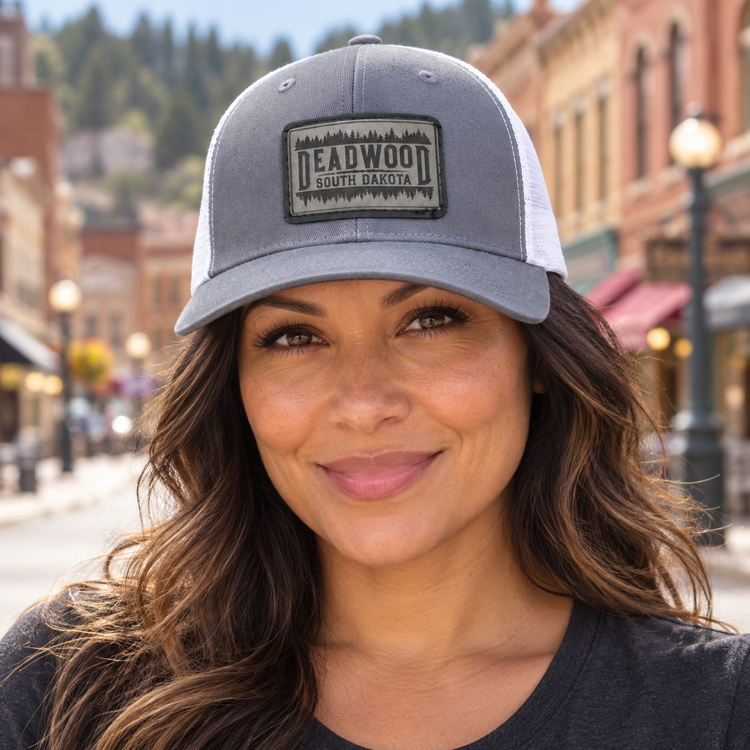 Female model wearing gray and white Deadwood South Dakota leather patch hat; AI-generated lifestyle image