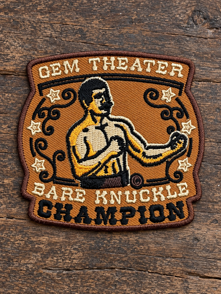 Gem Theater Bare Knuckle Champion Embroidered Patch — on weathered wood