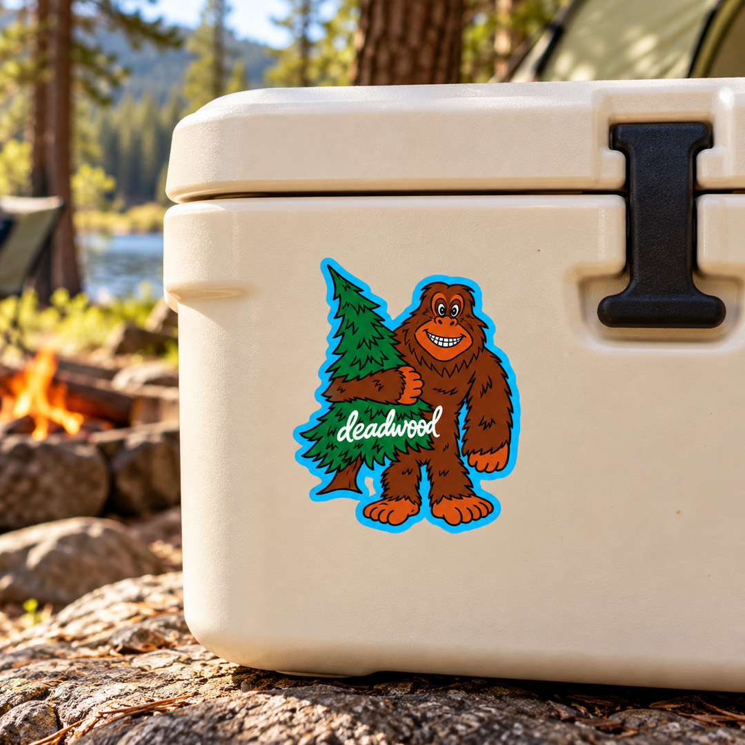 Deadwood Smiling Bigfoot Hugging a Pine Tree Sticker on a cooler — lifestyle display mockup; accessories not included