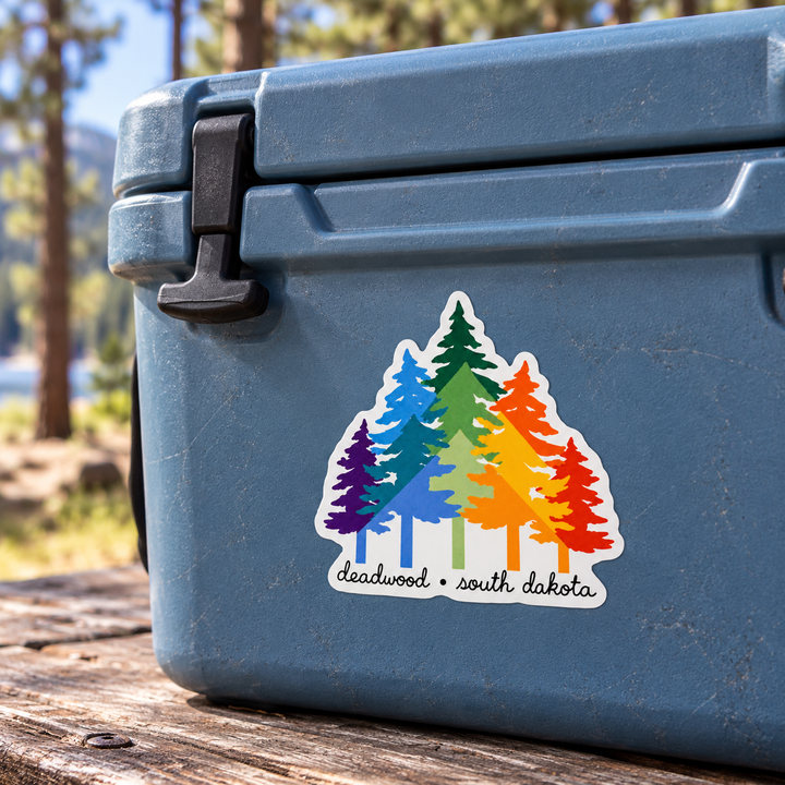Deadwood Rainbow Pine Trees Sticker shown on a cooler — lifestyle mockup