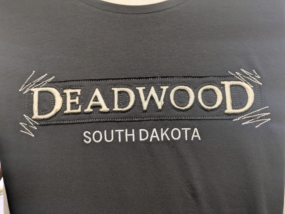 Close-up of Deadwood textile appliqué with cream lettering and embroidered zigzag corners
