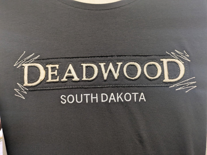 Close-up of Deadwood textile appliqué with cream lettering and embroidered zigzag corners